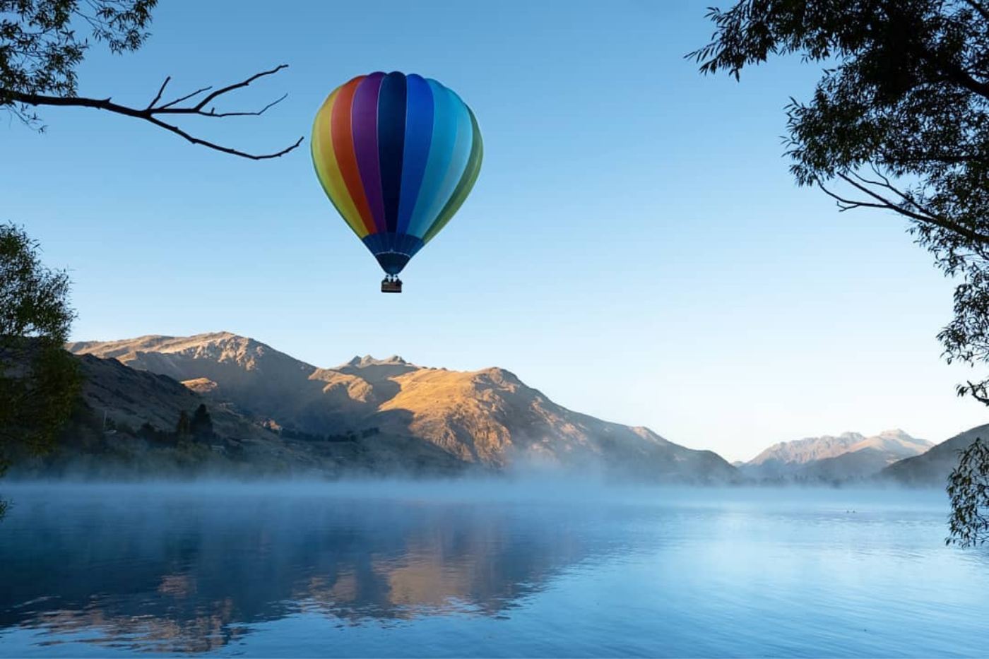 Hot air balloon flying over misty lake