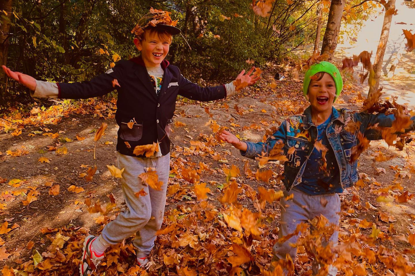 Two kids playing in autumn leaves
