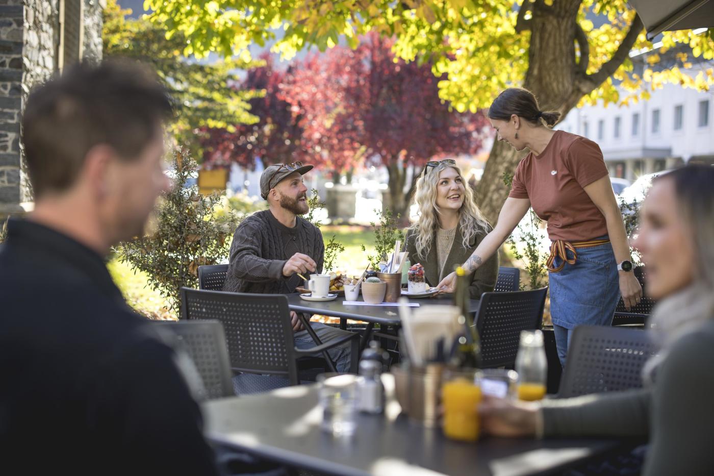 Waitress serving customers in a pretty outdoor autumn setting