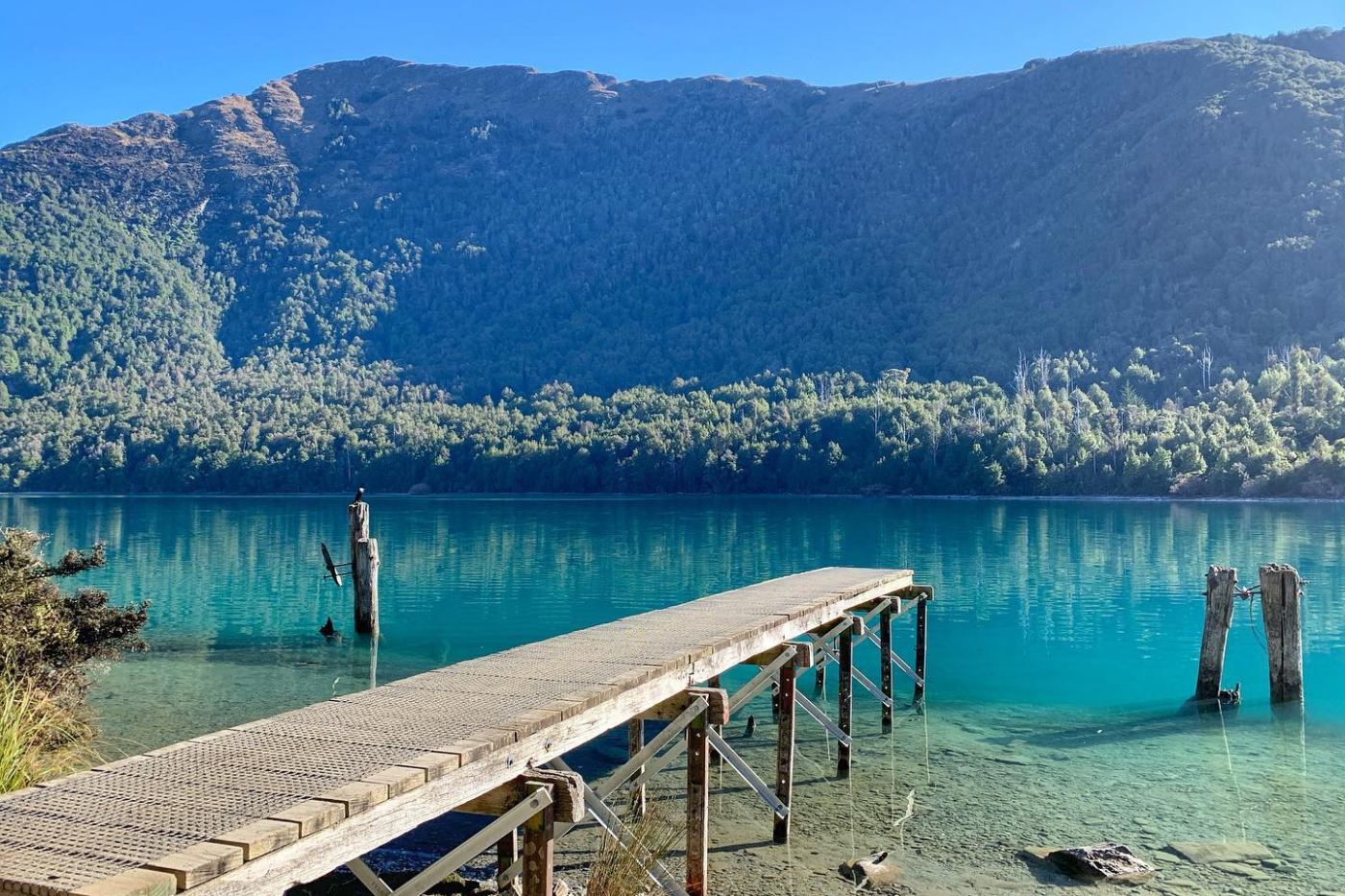 View of jetty over blue lake with mountain in background