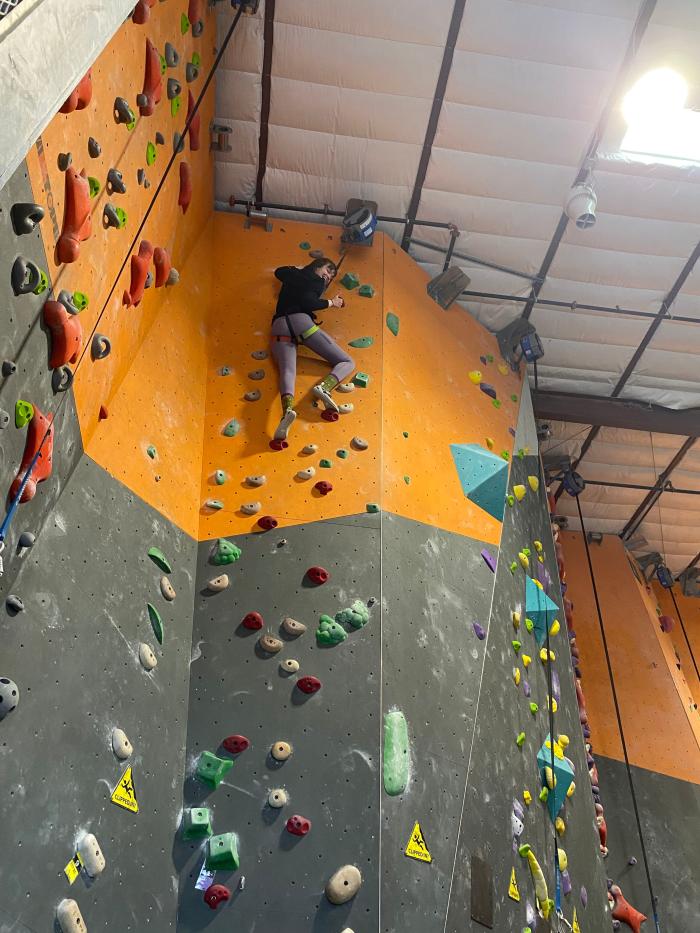 Visit Albuquerque employee Sarah gives a thumbs up from the top of a beginner climbing wall at Stone Age Climbing Gym