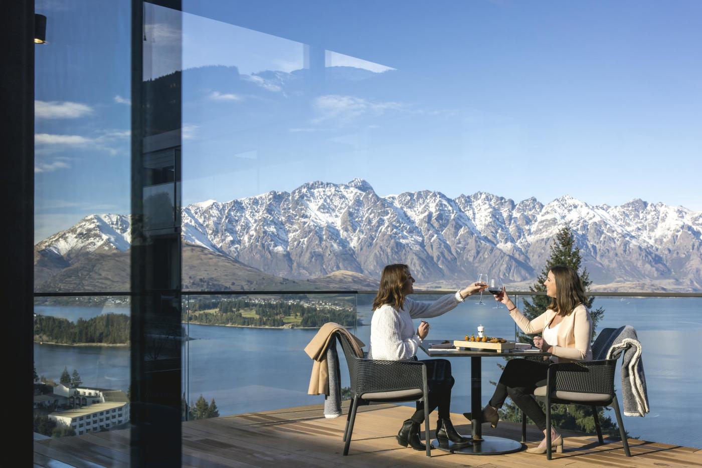 People dining outside with snow capped mountains in the background