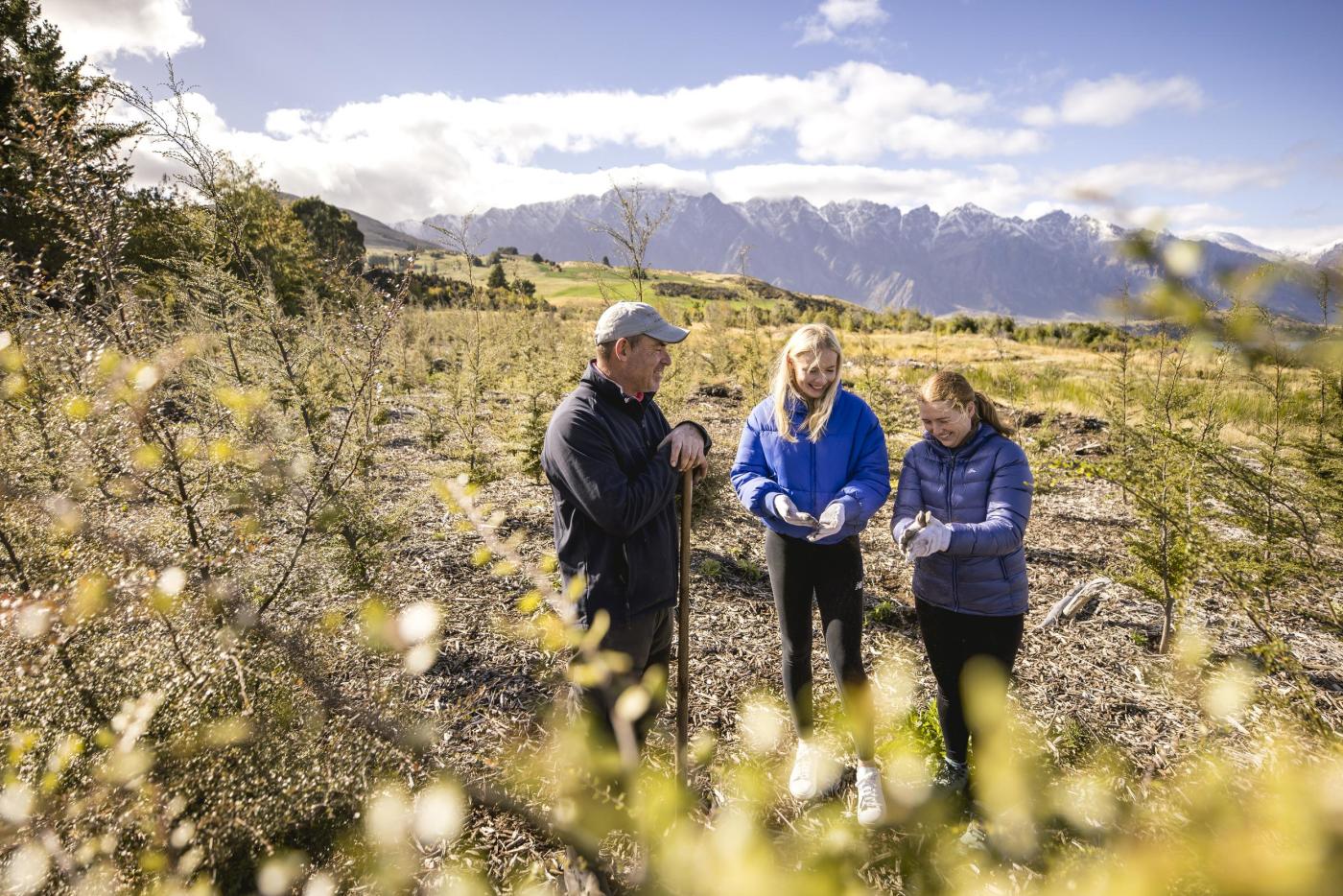 3 people working at a planting site in Queenstown, planting native trees to reforest the area with native bush