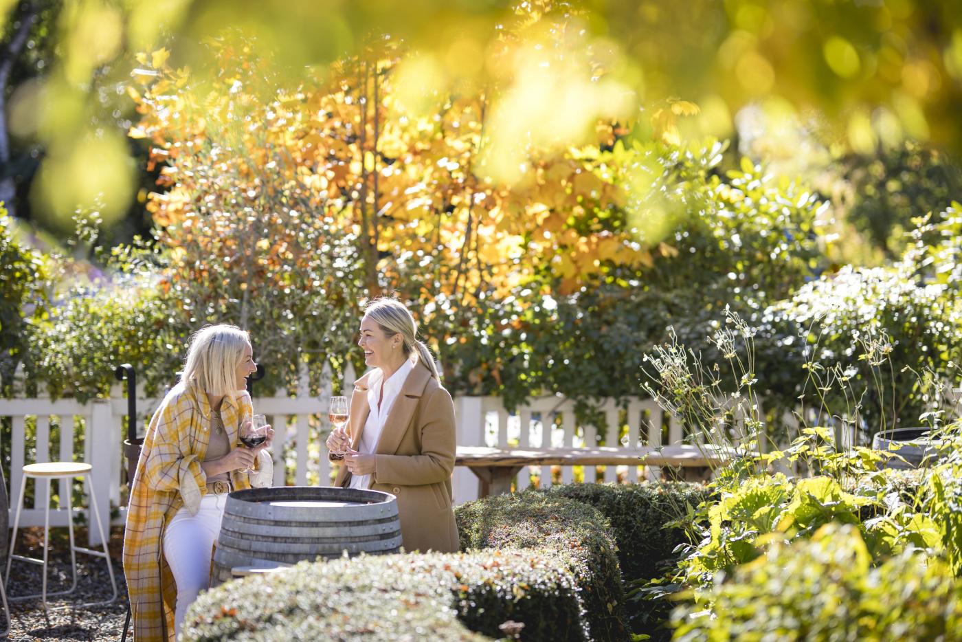 Two people enjoying wine in a outdoor garden dining aera in autumn