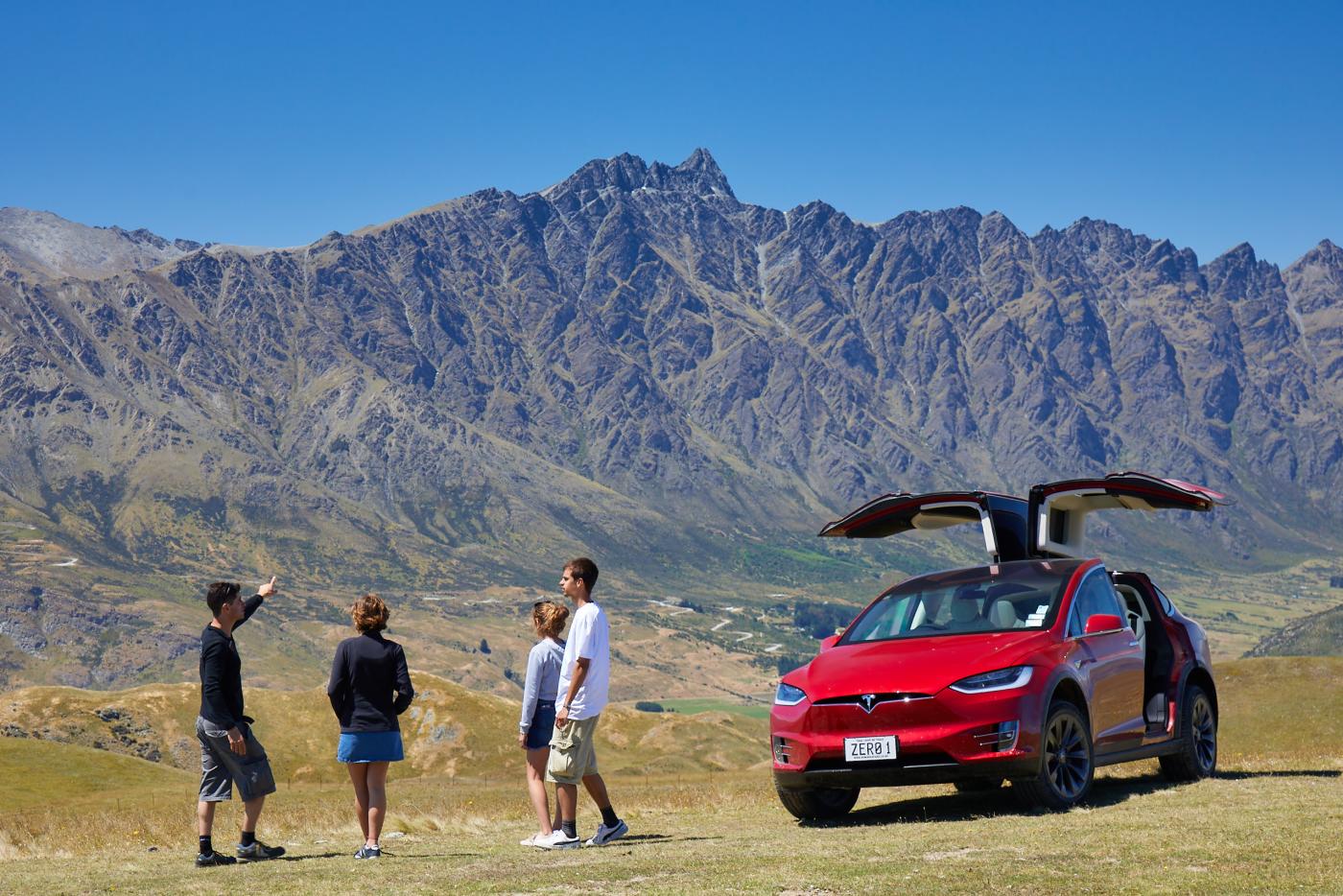 Family on Nomad Safari's Tesla Scenic Tour in front of the Remarkables mountains