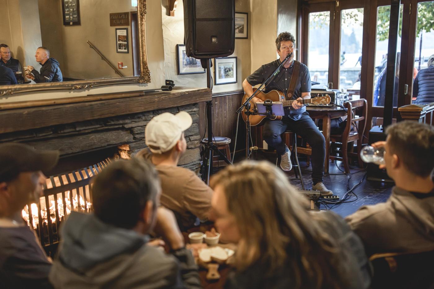 Musician playing guitar to people at Pog Mahones Irish Pub