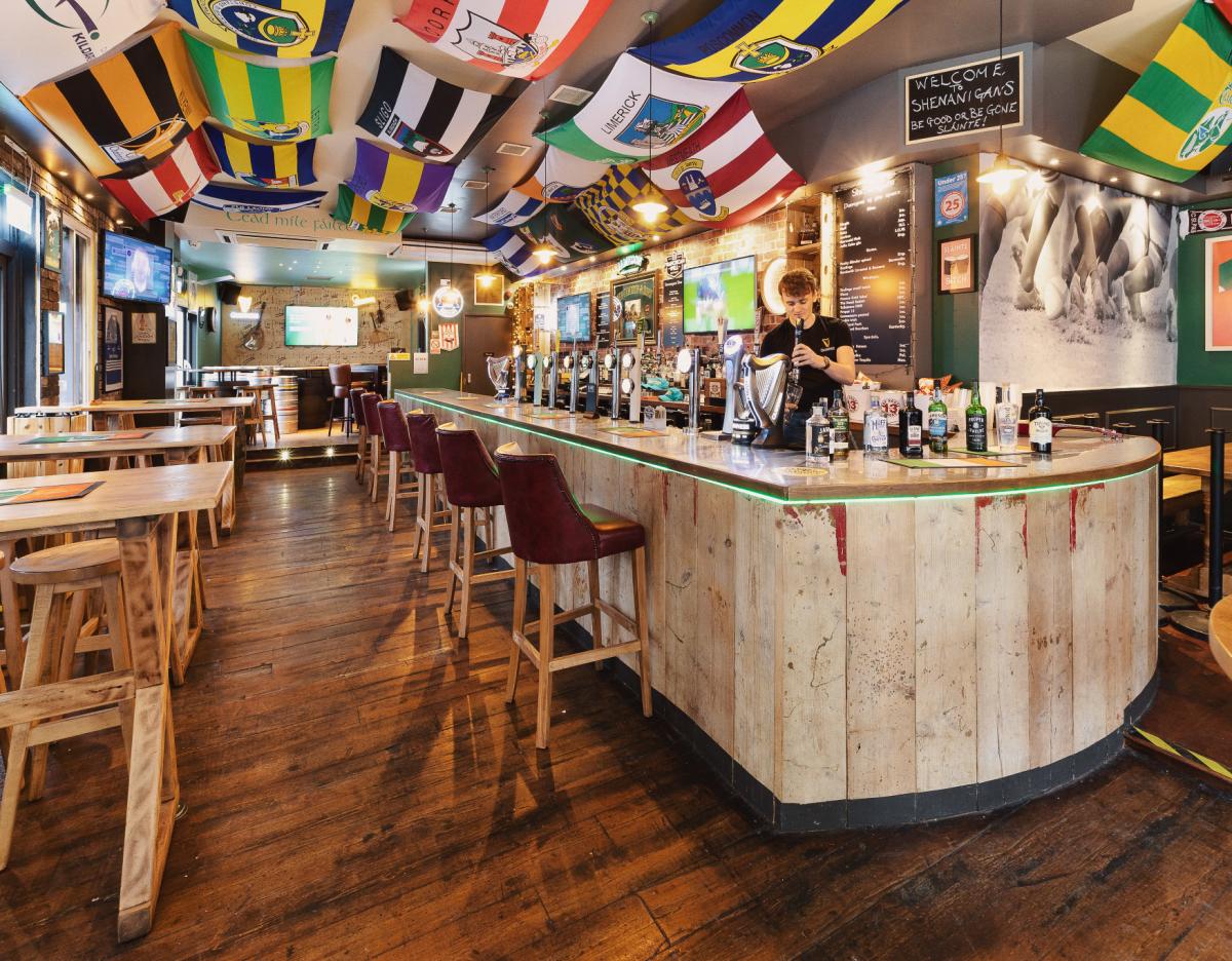 Interior of Shenanigans' bar area with an assortment of sports flags hanging from the ceiling