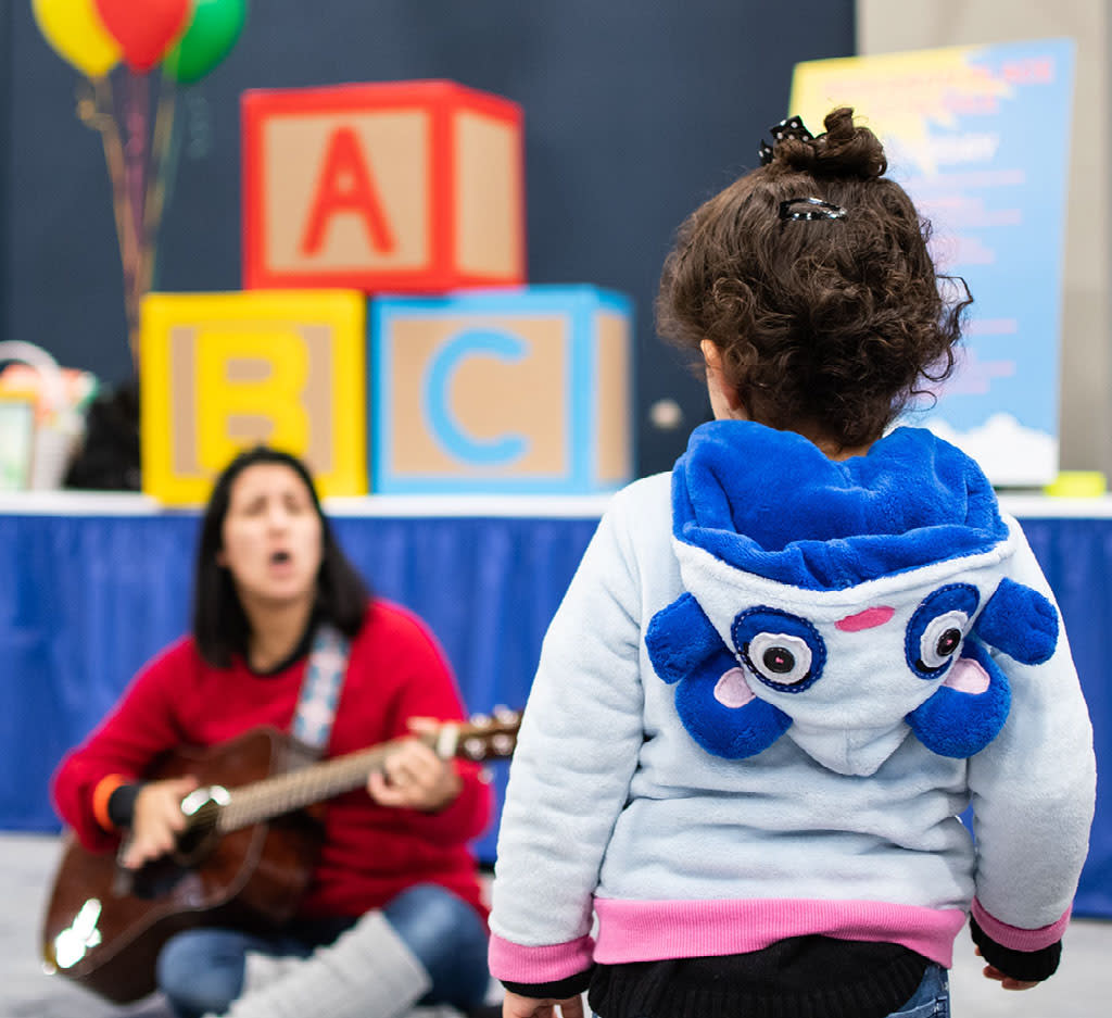 Toddler listening to woman play guitar during The Children's Festival at The Cynthia Woods Mitchell Pavilion