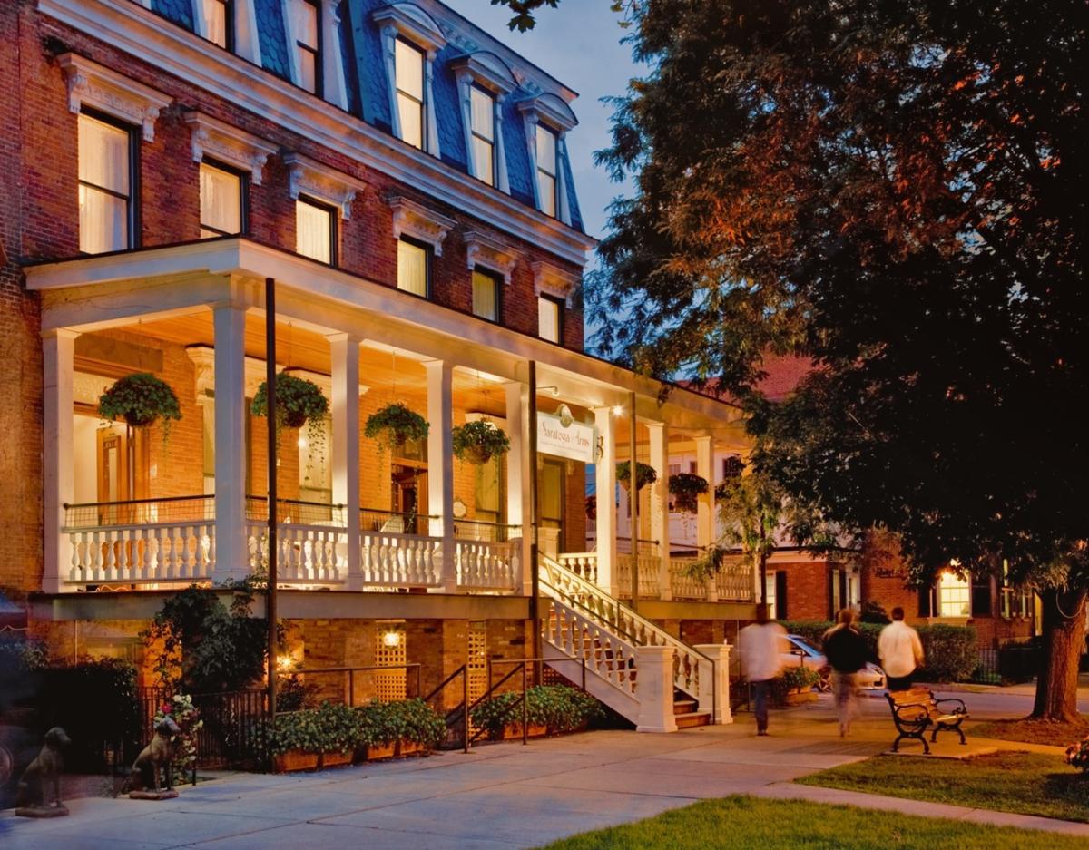 View of front porch from sidewalk at dusk, porch lit up.