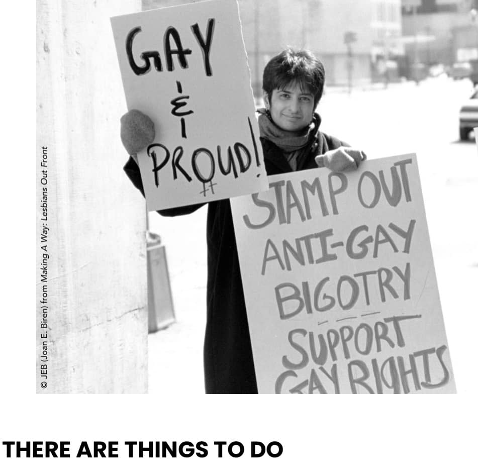Black and white photo of a woman with short hair. She holds two signs, one says "Gay and Proud!". The other states "Stamp Out Anti-Gay Bigotry. Support Gay Rights". At the bottom is the movie title, There Are Things To Do.