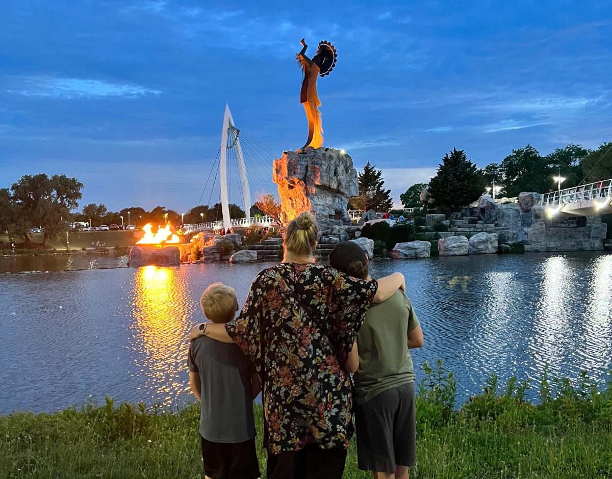 A mother and her two sons look at the Keeper of the Plains at dusk in Wichita
