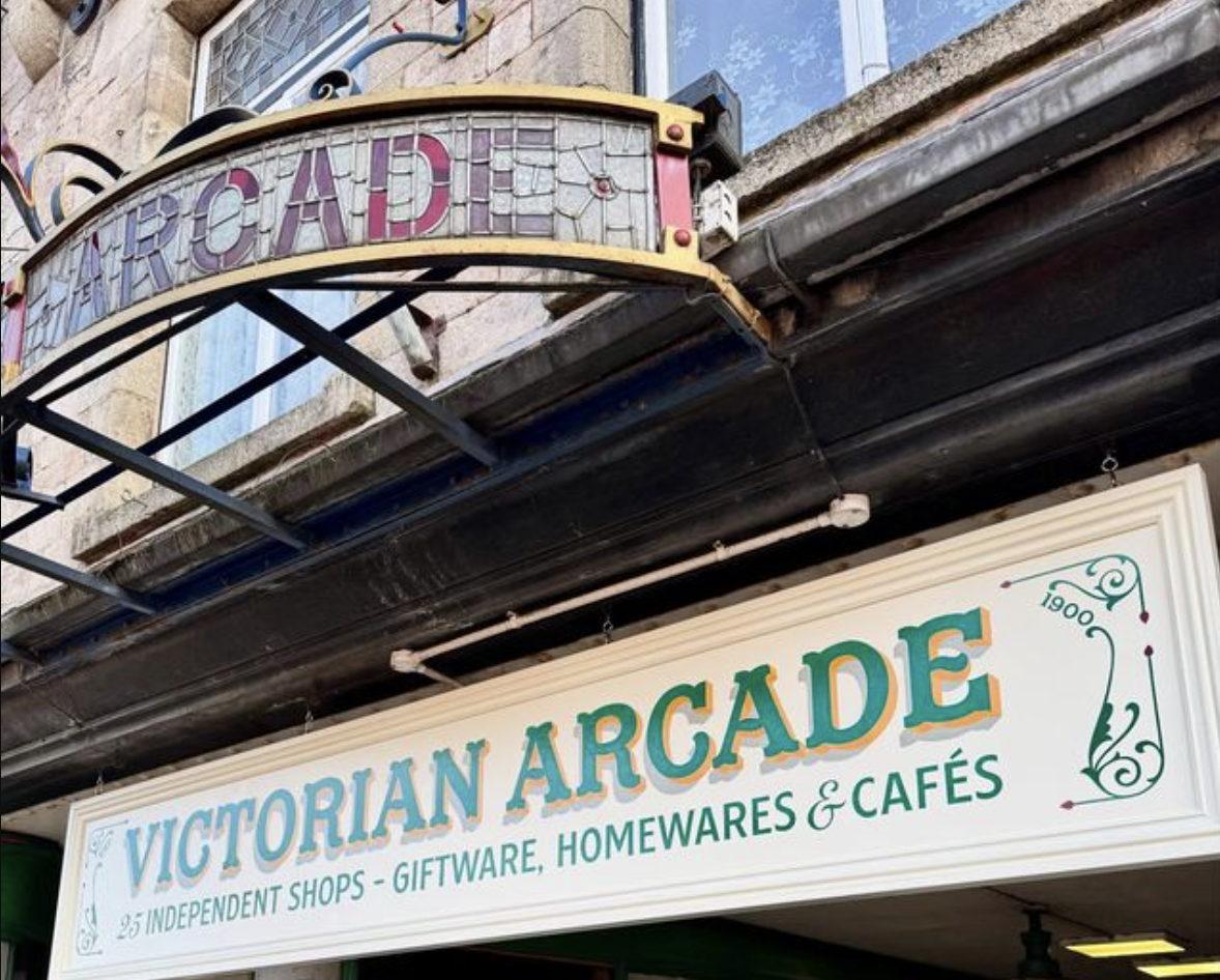 Signage for Victorian Arcade, featuring decorative stained glass reading "ARCADE" above, and a white sign below with "VICTORIAN ARCADE" in green letters.