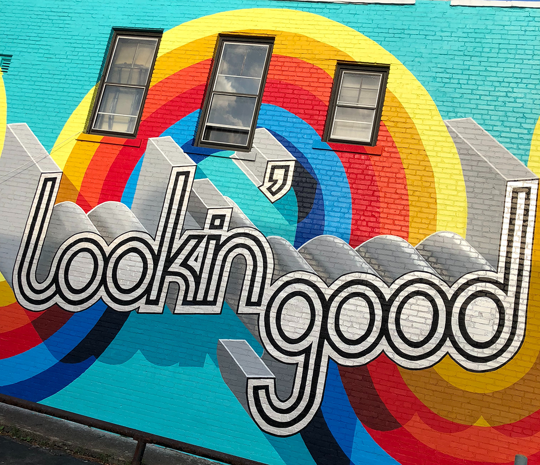 wall mural that says lookin' good with rainbow design in background