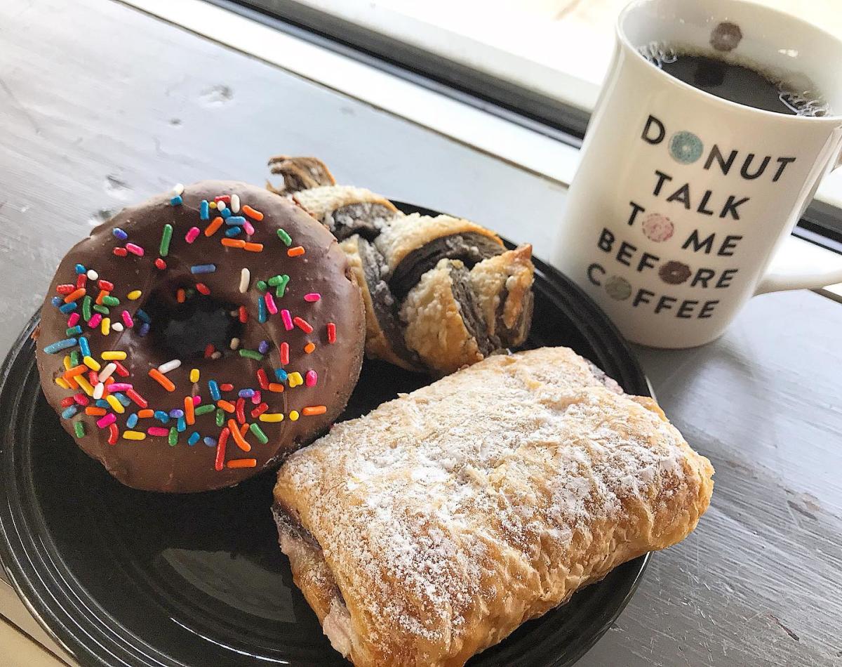 Image is of donuts, pastries and a coffee mug that say's "Donut Talk To Me Before Coffee".