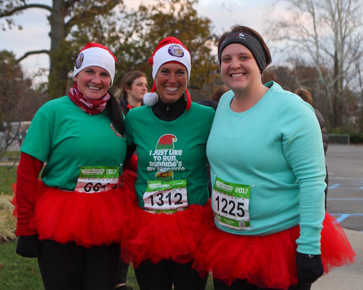 three women wearing green shirts and red tutu skirts after running a holiday 5k race