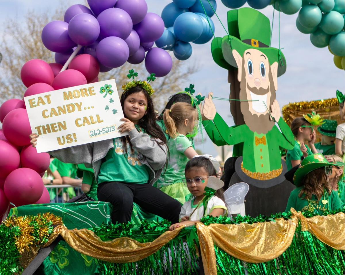 Kids hold up a sign while riding a float in the Paddy Day Parade