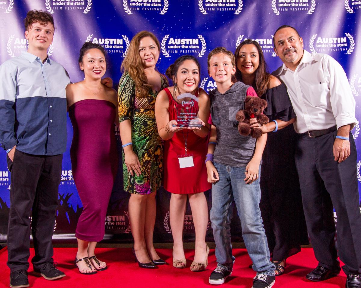 Image of a group of people holding their trophy after winning an award at the Austin Under the Stars Film Festival.