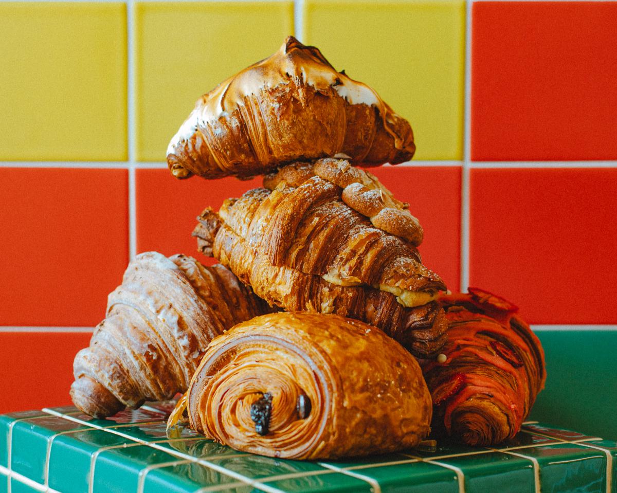 Image of a pile of different flavored croissants piled on top of one another sitting in front of a brightly colored tile wall at ROCKMAN.