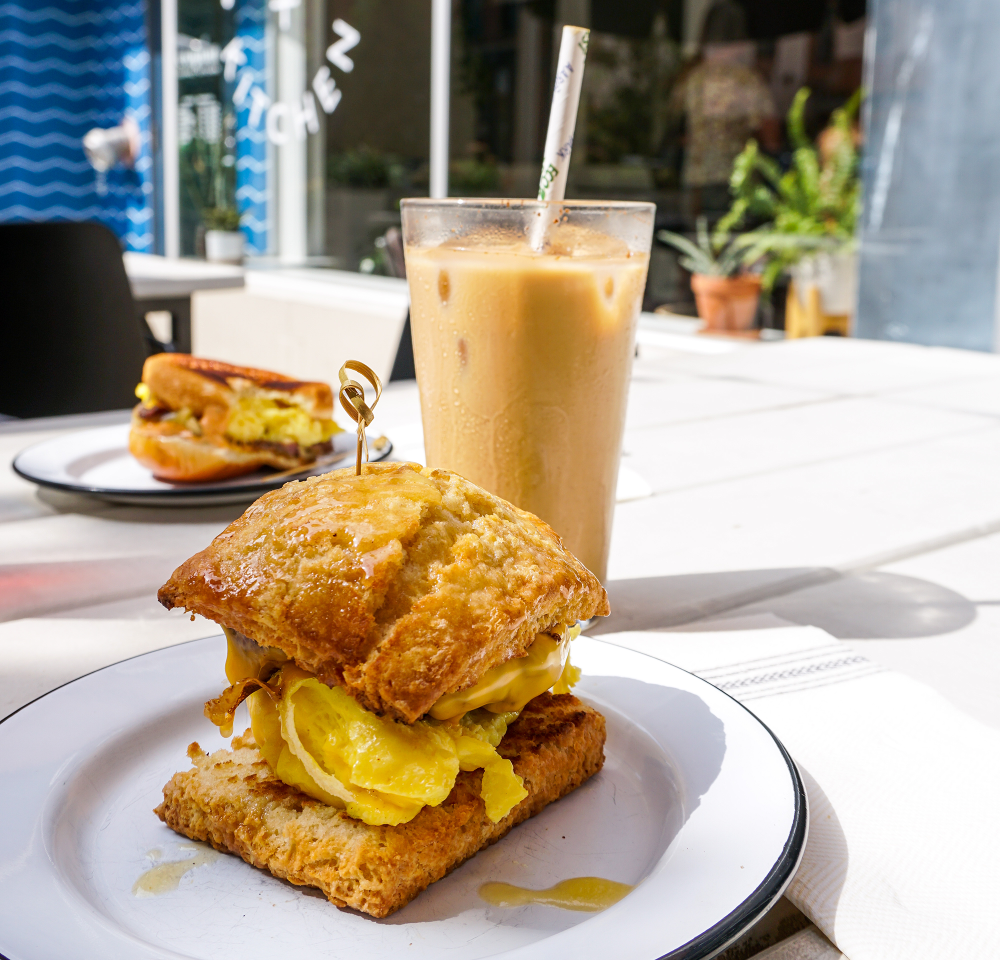 scrambled eggs on a biscuit and a pint glass with iced coffee