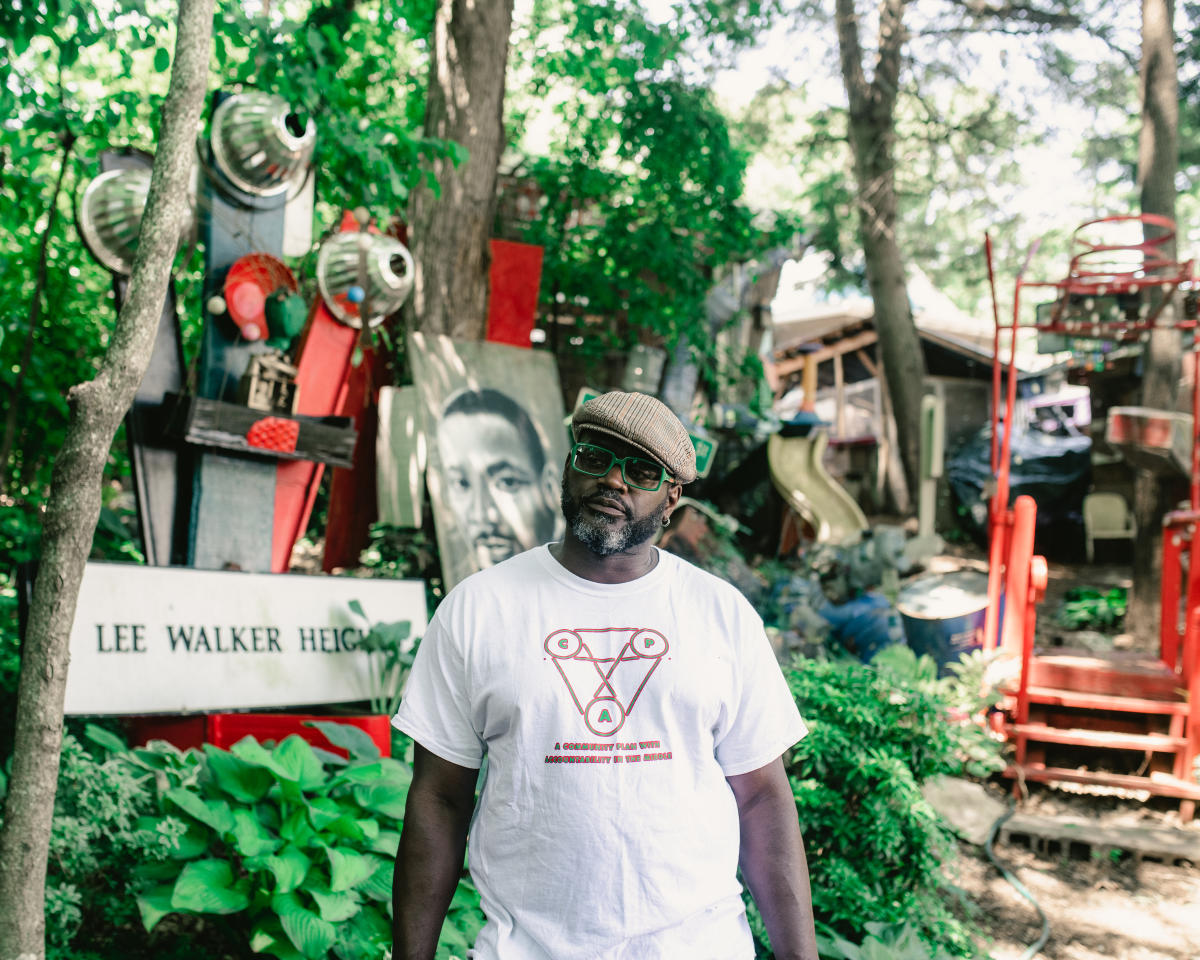 DeWayne Barton stands in front of art at Peace Gardens & Market in West Asheville