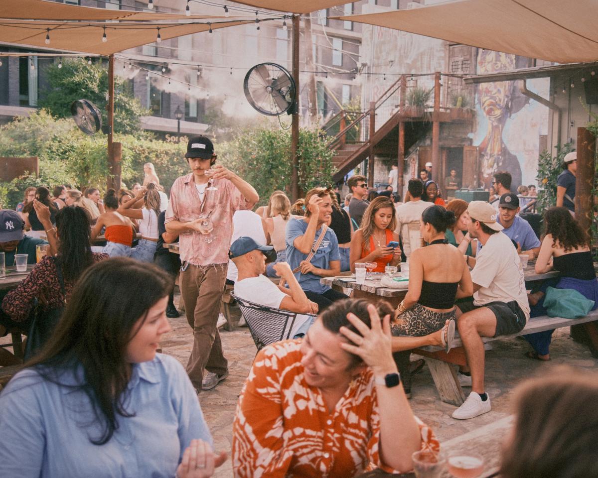 Image of people hanging out and sitting at picnic tables on the outdoor patio at Whisler's.