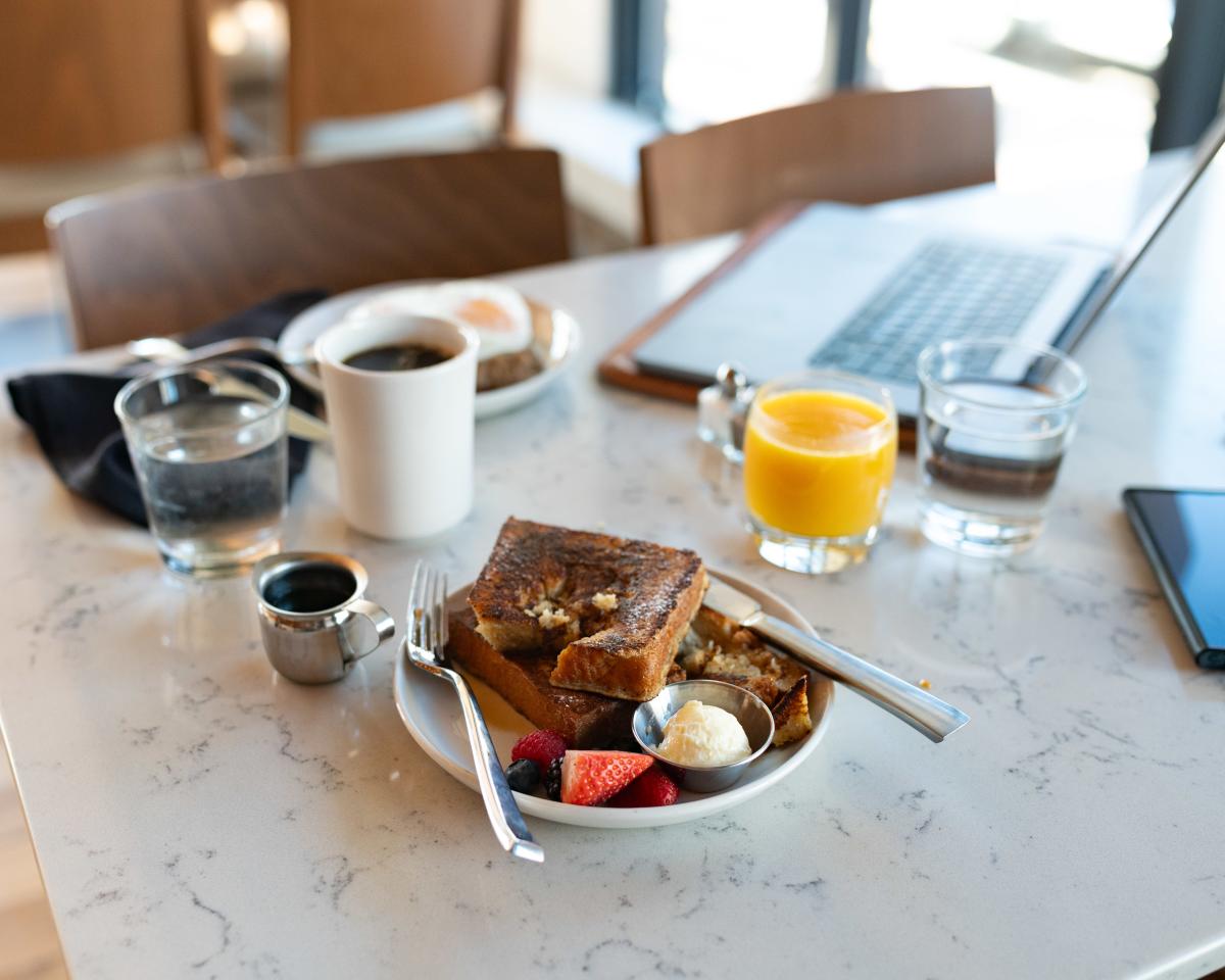 A laptop sitting next to a breakfast plate and coffee at The Informalist