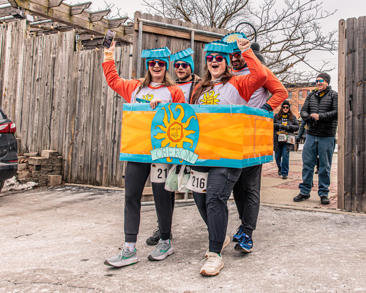 Four individuals dressed with blue bottle-cap hats simulate a Bell's Oberon four pack during Bell's Brewery Snow Jog.