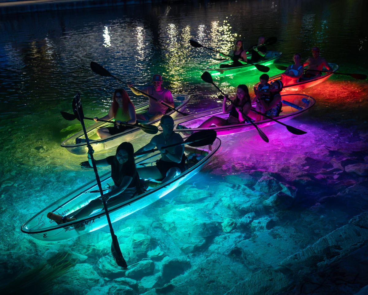 A group take a glow kayak tour on the San Marcos River