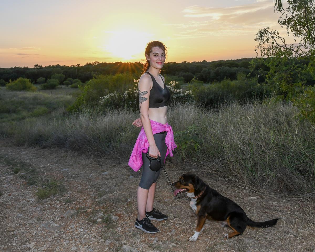 Woman smiling at camera on Purgatory Creek trail with dog