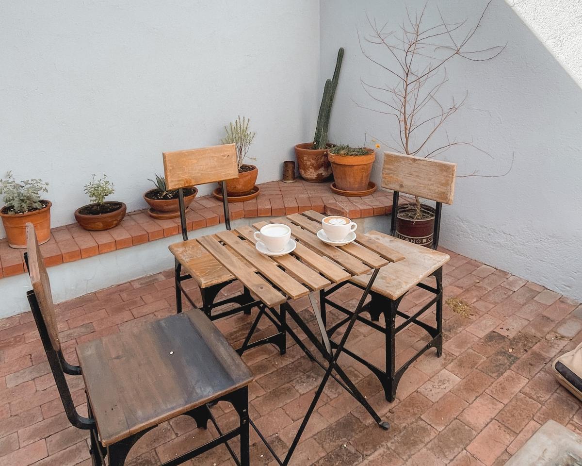 Outdoor Patio with small table with three seats around it. Two mugs sit on top of the table