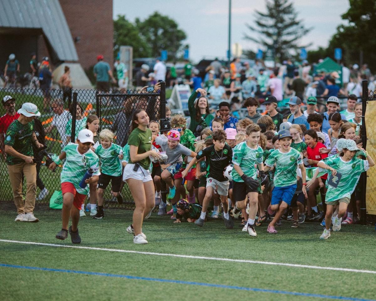 Children running out onto Virtue Field in Vermont Green FC's jerseys.