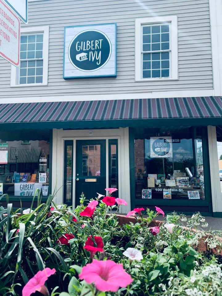 The storefront of Gilbert & Ivy bookstore has flowers in front of it.