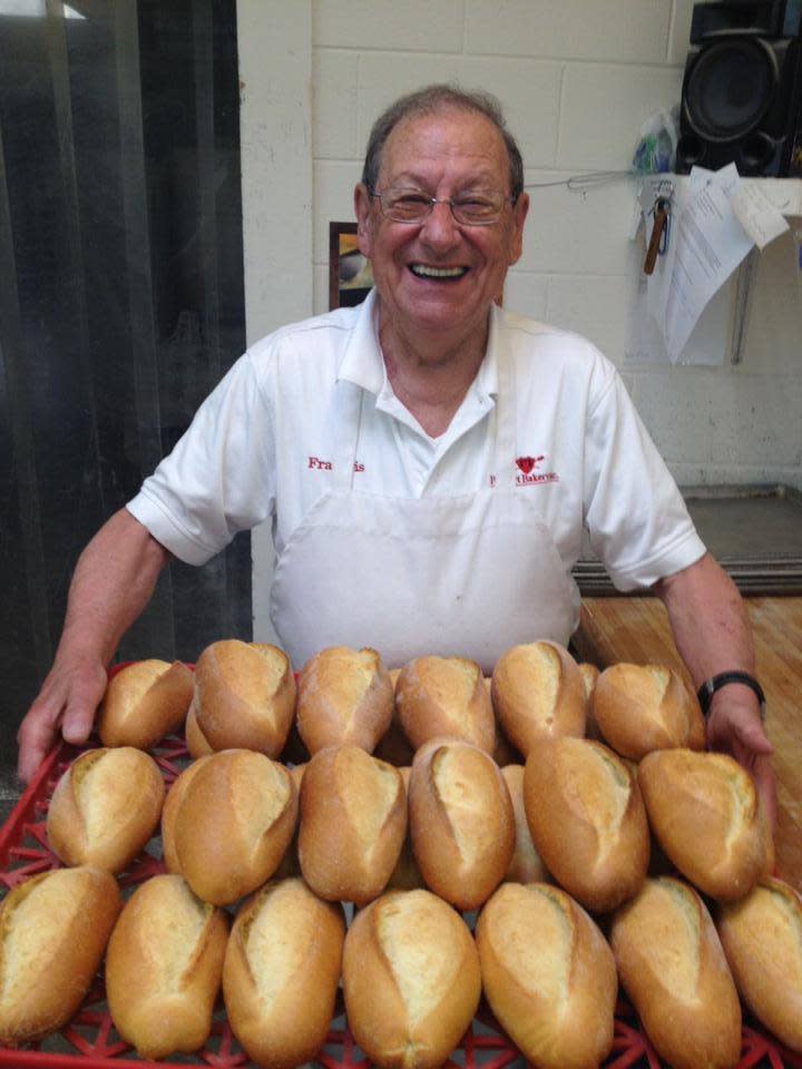 A baker holding a tray of bread At Poupart's In Lafayette, LA