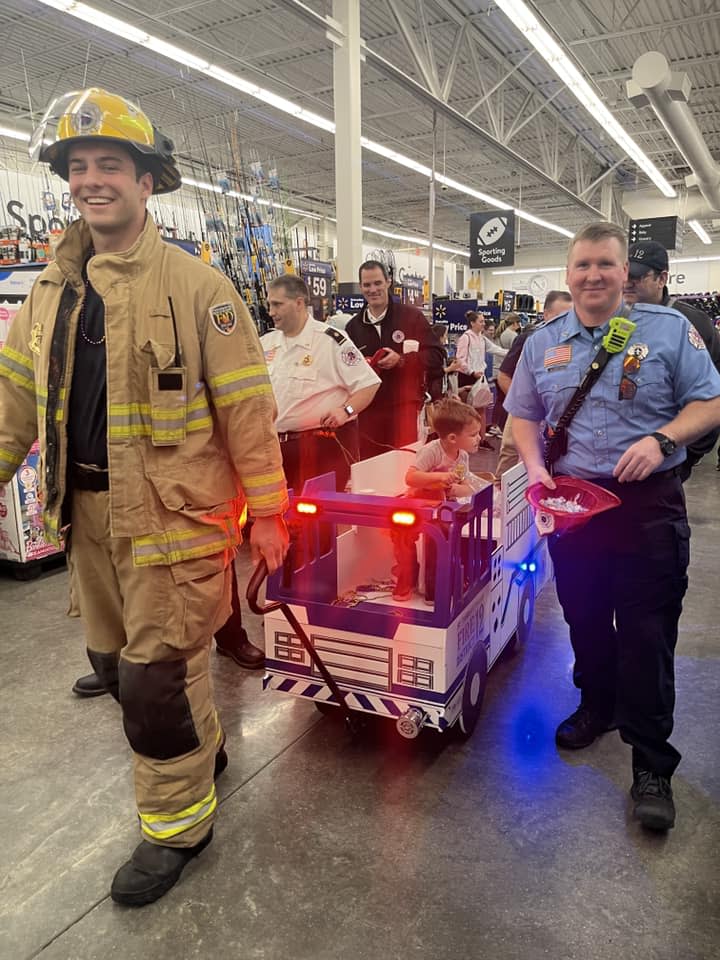 A firefighter and police officer walk alongside a mini-firetruck in Covington Walmart Supercenter's annual Mardi Gras parade for special needs kids. A child rides in the small truck and other first responders trail behind.