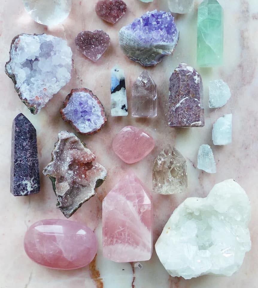 Image is of a variety of crystals on a granite counter top.