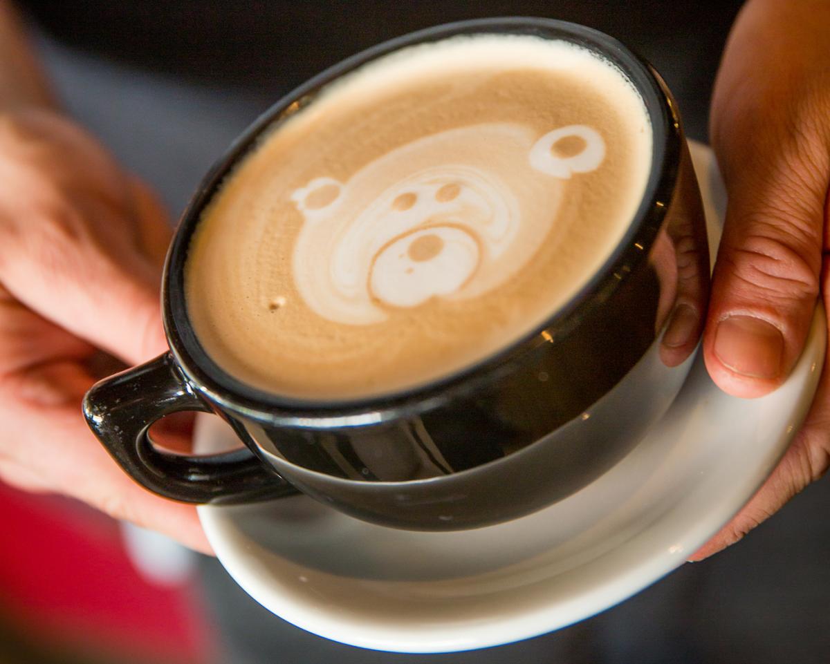 Hot latte in a mug with a bear design on top at Cafe Nola