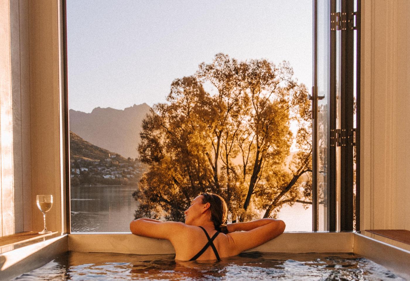 Person in hot tub with mountain and lake views in the background