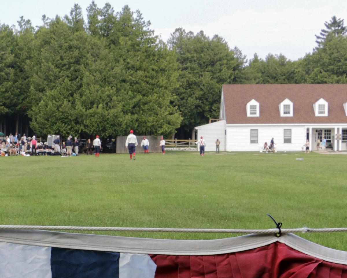 Red, white and blue bunting hangs around the outfield during a vintage base ball game on Mackinac Island