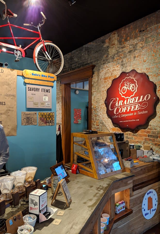 Carabello Coffee sign hanging on a brick wall over a counter with coffees and pastries