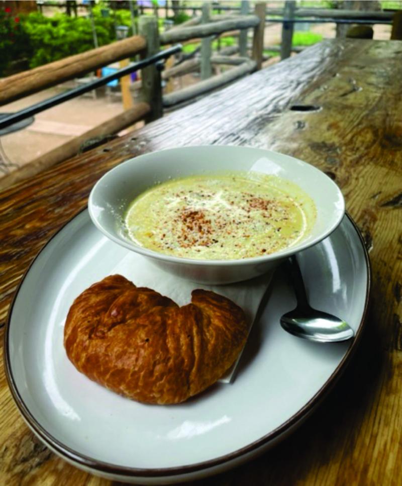 A bowl of green chile corn chowder and a croissant from Bike In Coffee