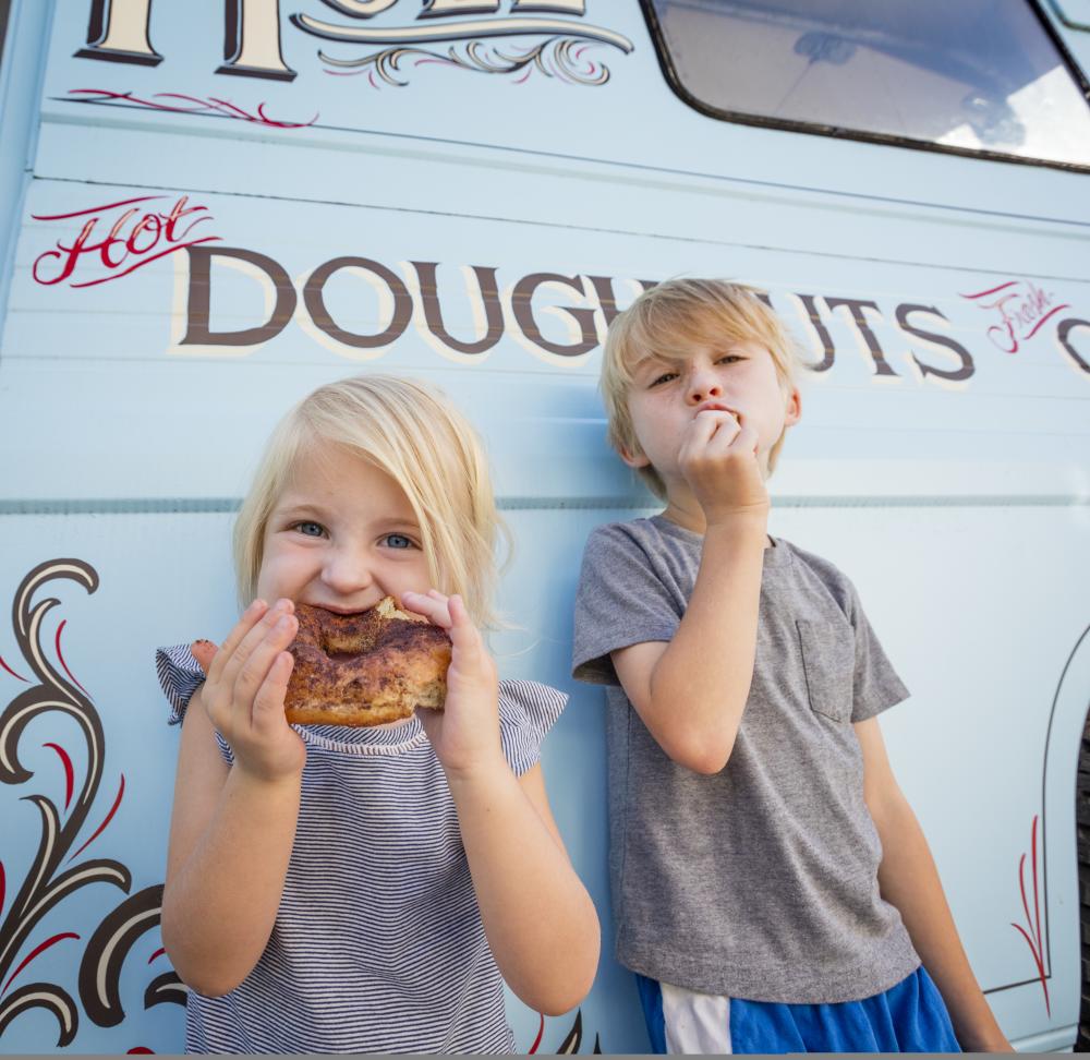 Little girl eating doughnut outside of Hole Doughnut