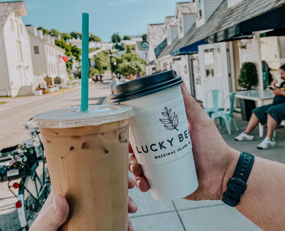 Two cups of coffee from Lucky Bean with a downtown Mackinac Island street in the background