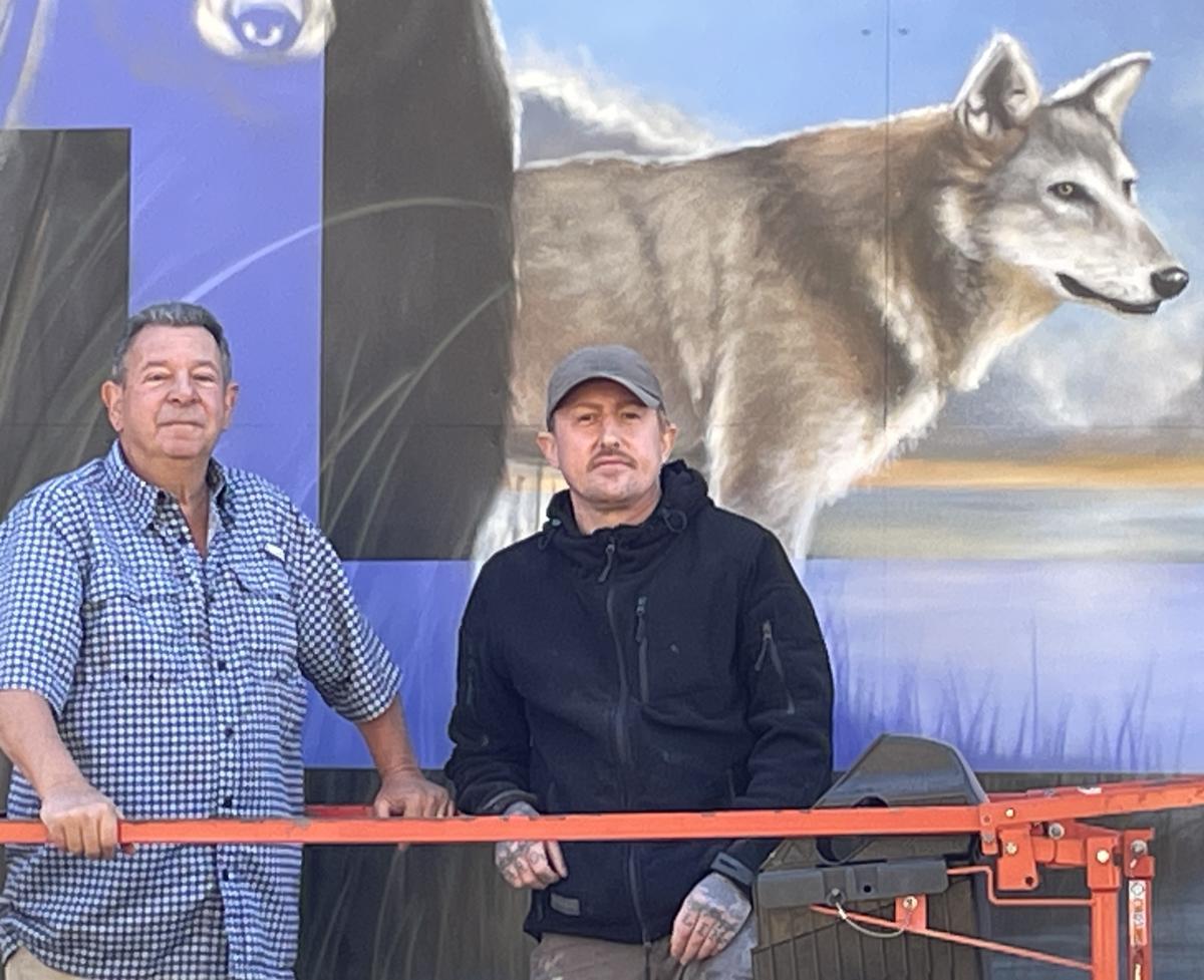 Artist Brian Lewis stands in front of the Tuscarora Native American Mural he completed in Smithfield.