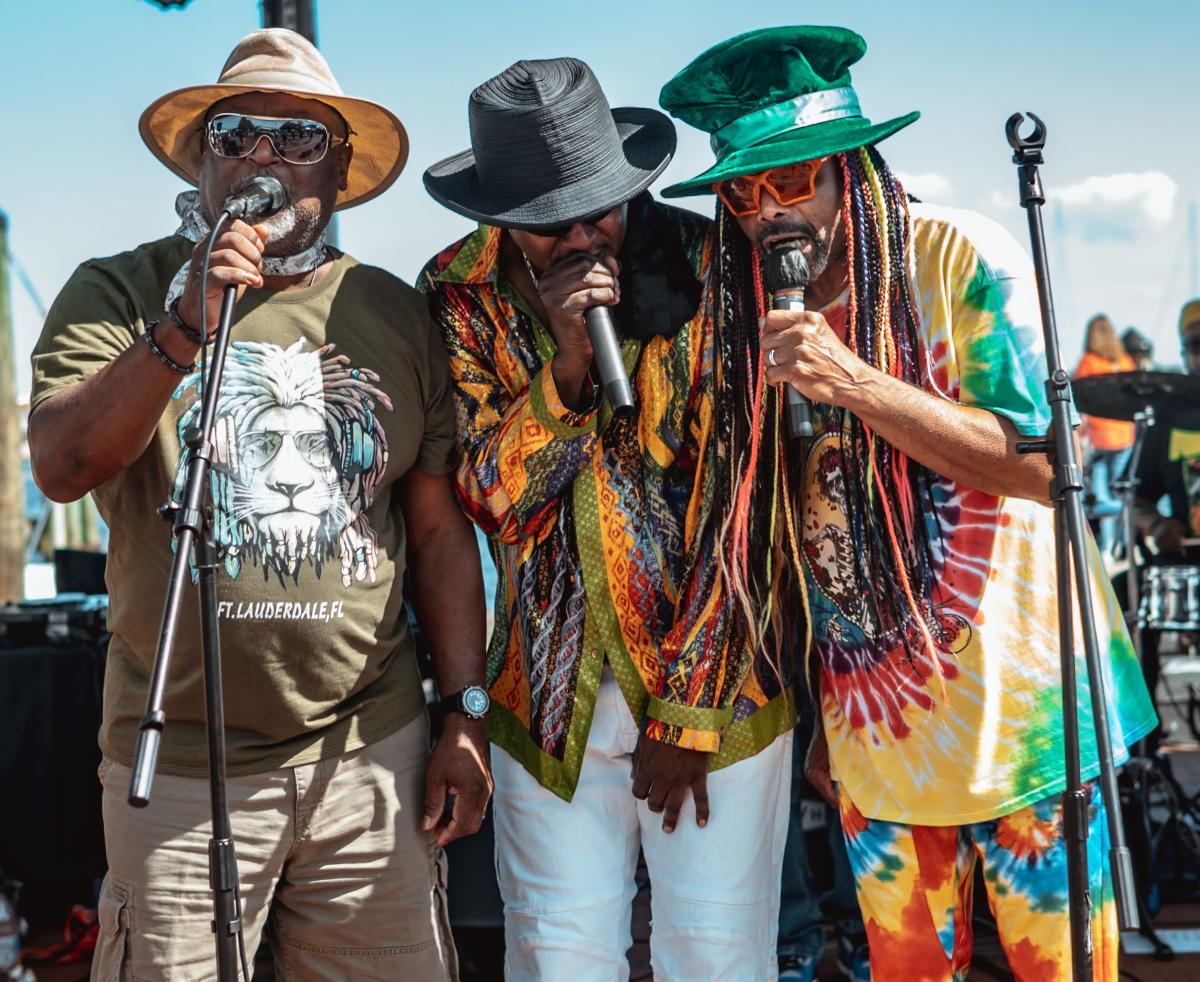 Three black men singing on a stage at Kunta Kinte Heritage Festival