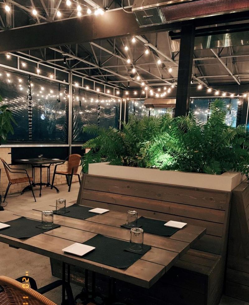 outdoor dining terrace with wooden tables and string lights