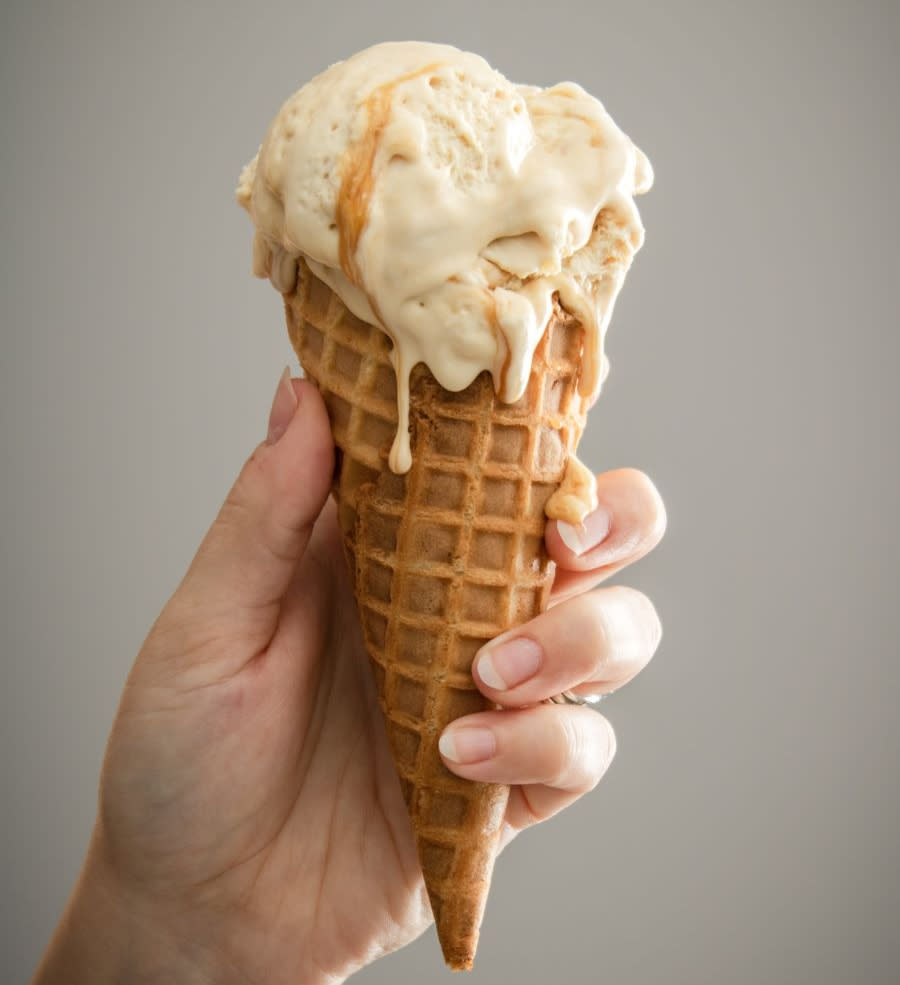 caramel swirl ice cream drips down waffle cone onto hand