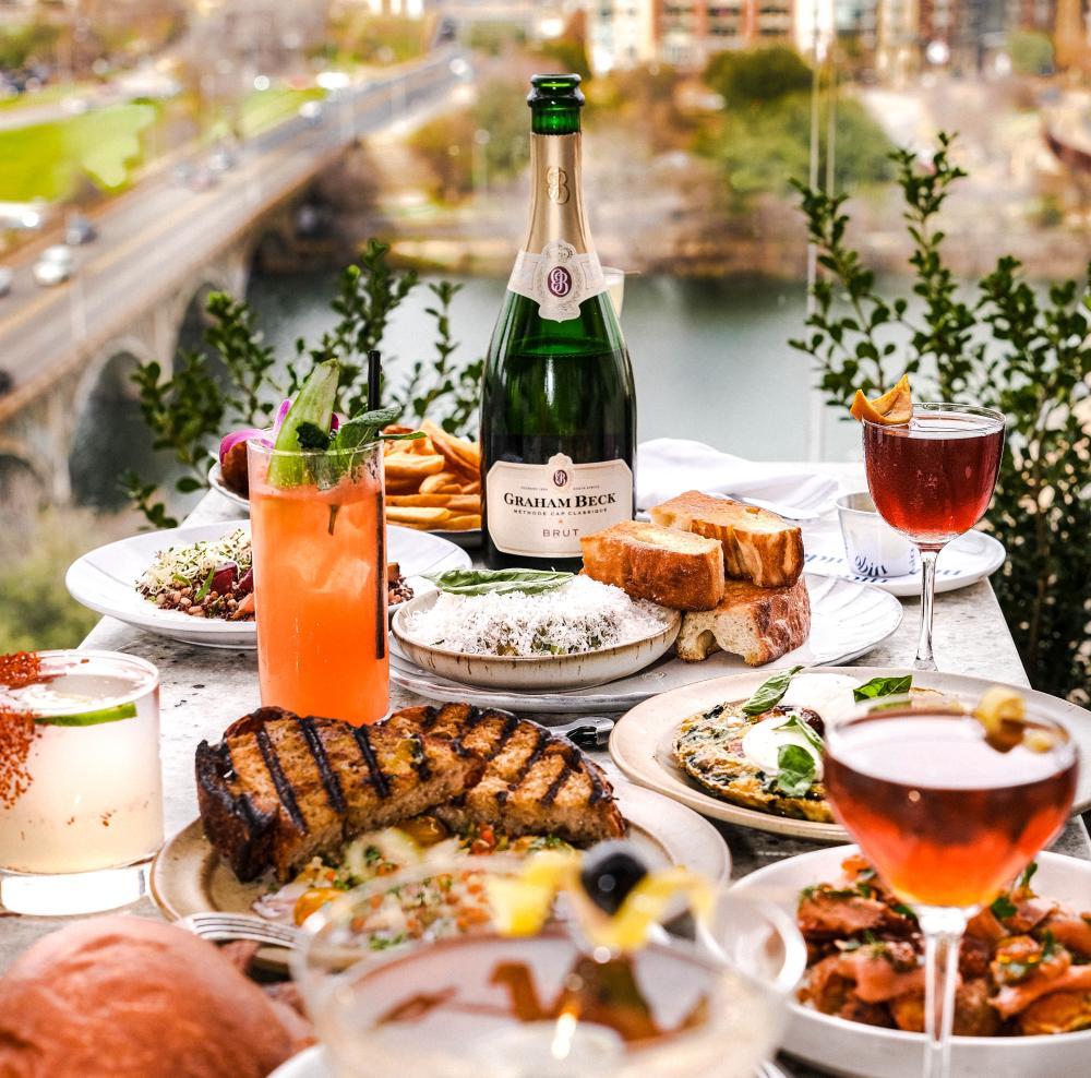 Image of a large spread of food and drinks on a patio table at Nido.