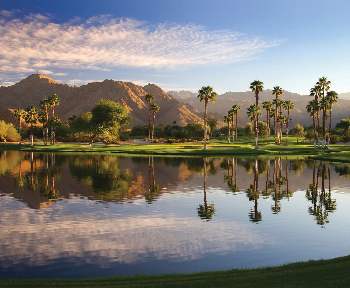 Beautiful lake at Indian Wells Golf Resort with the mountains, palm trees and green grass.