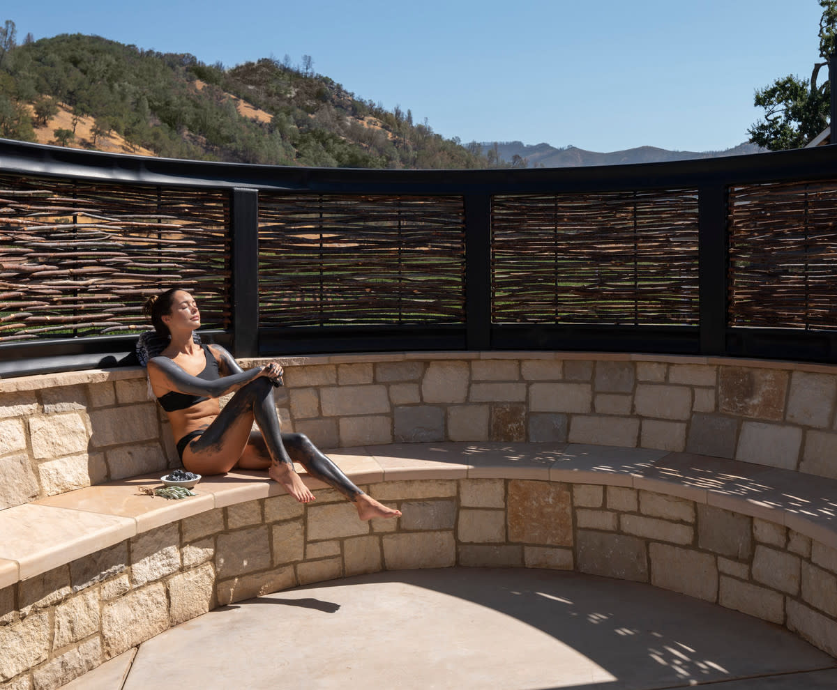 women with mud painted on her body sitting outside at Spa Talisa