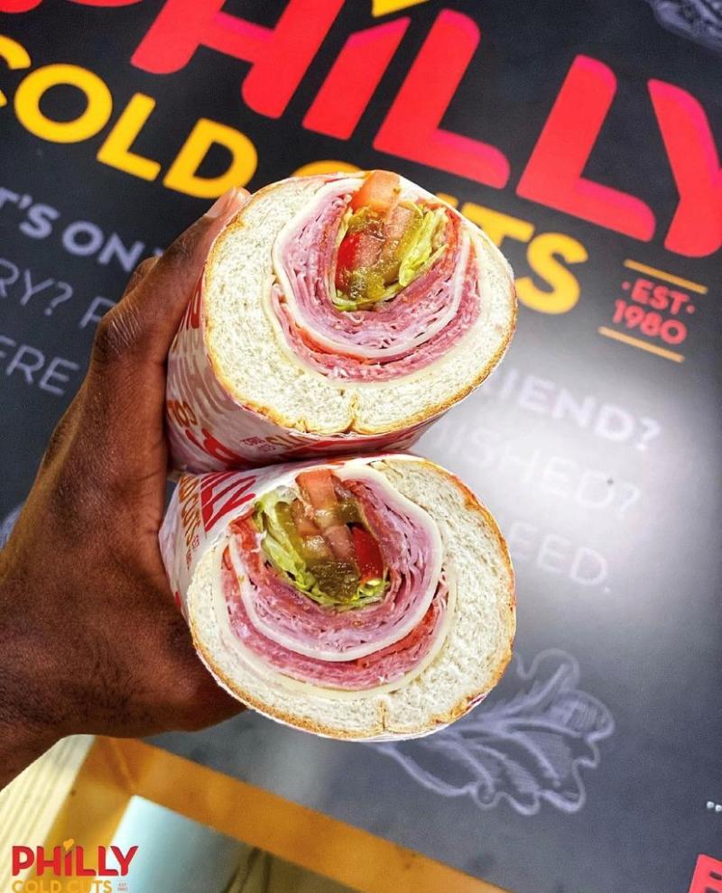 italian sub being held in front of a sign